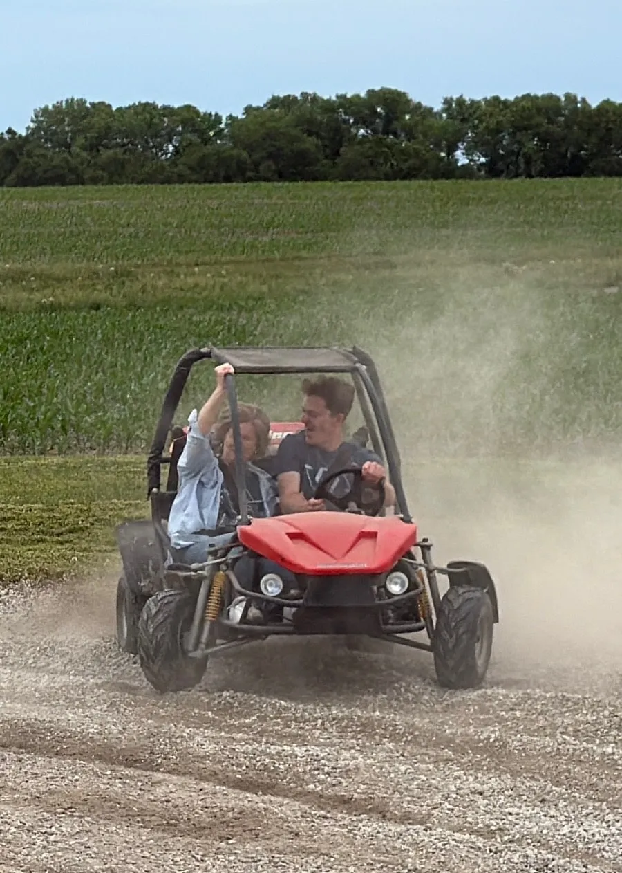 Driving a dune buggy down a dirt road, trailing dust