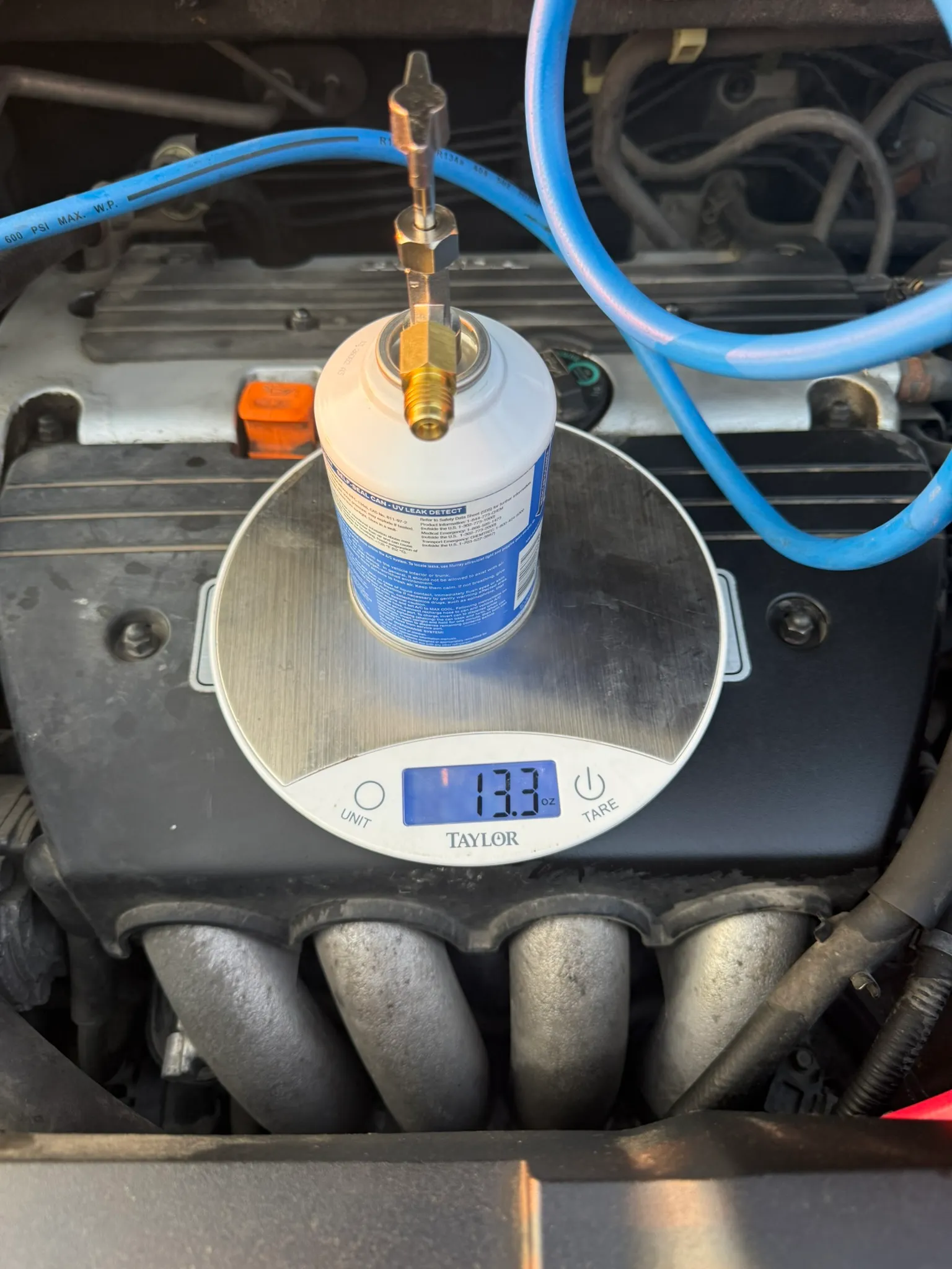 Refrigerant can inverted on a digital scale reading 13.3 oz during charging