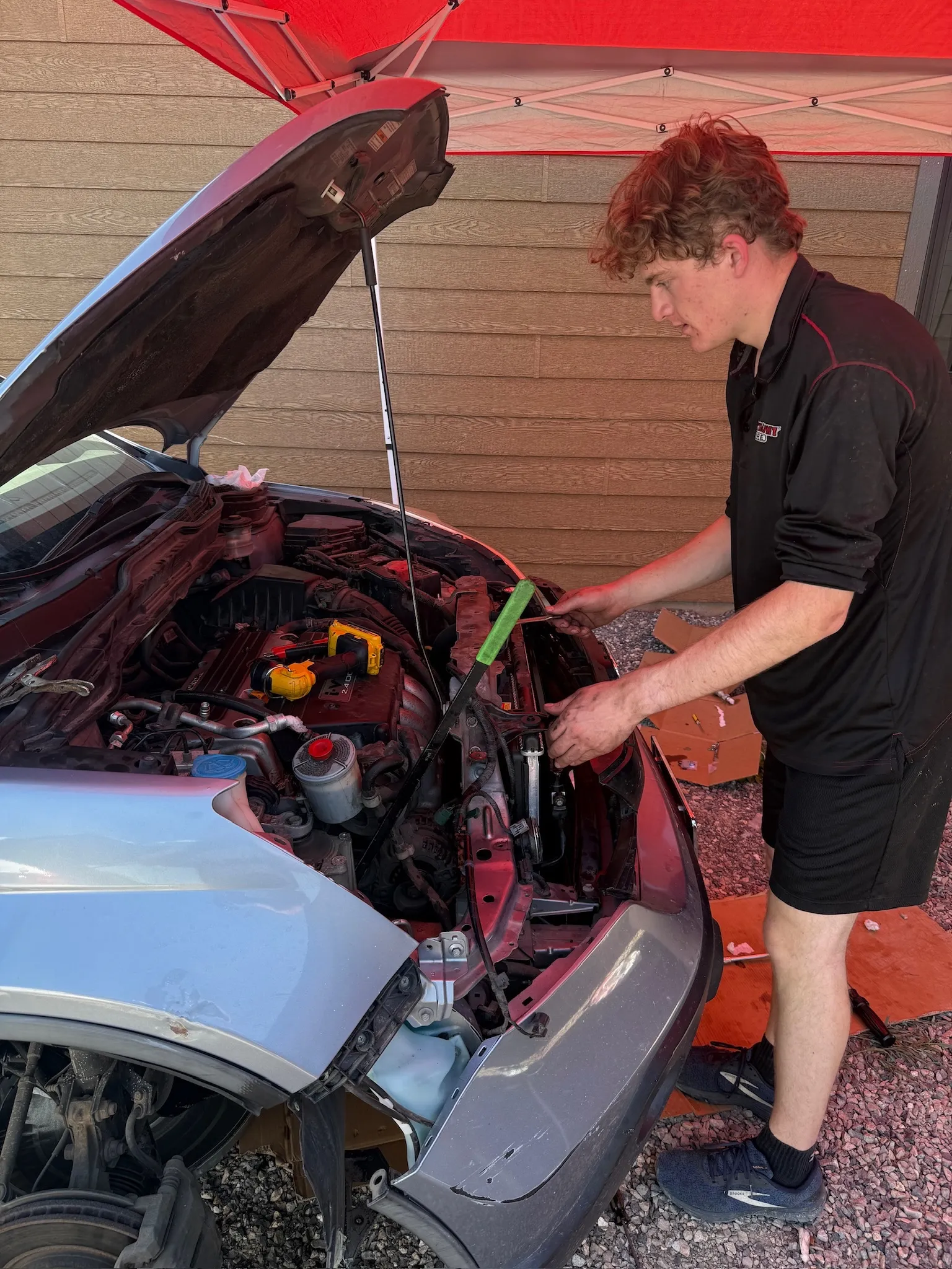 Jack working on the car A/C system under the hood in the rental driveway
