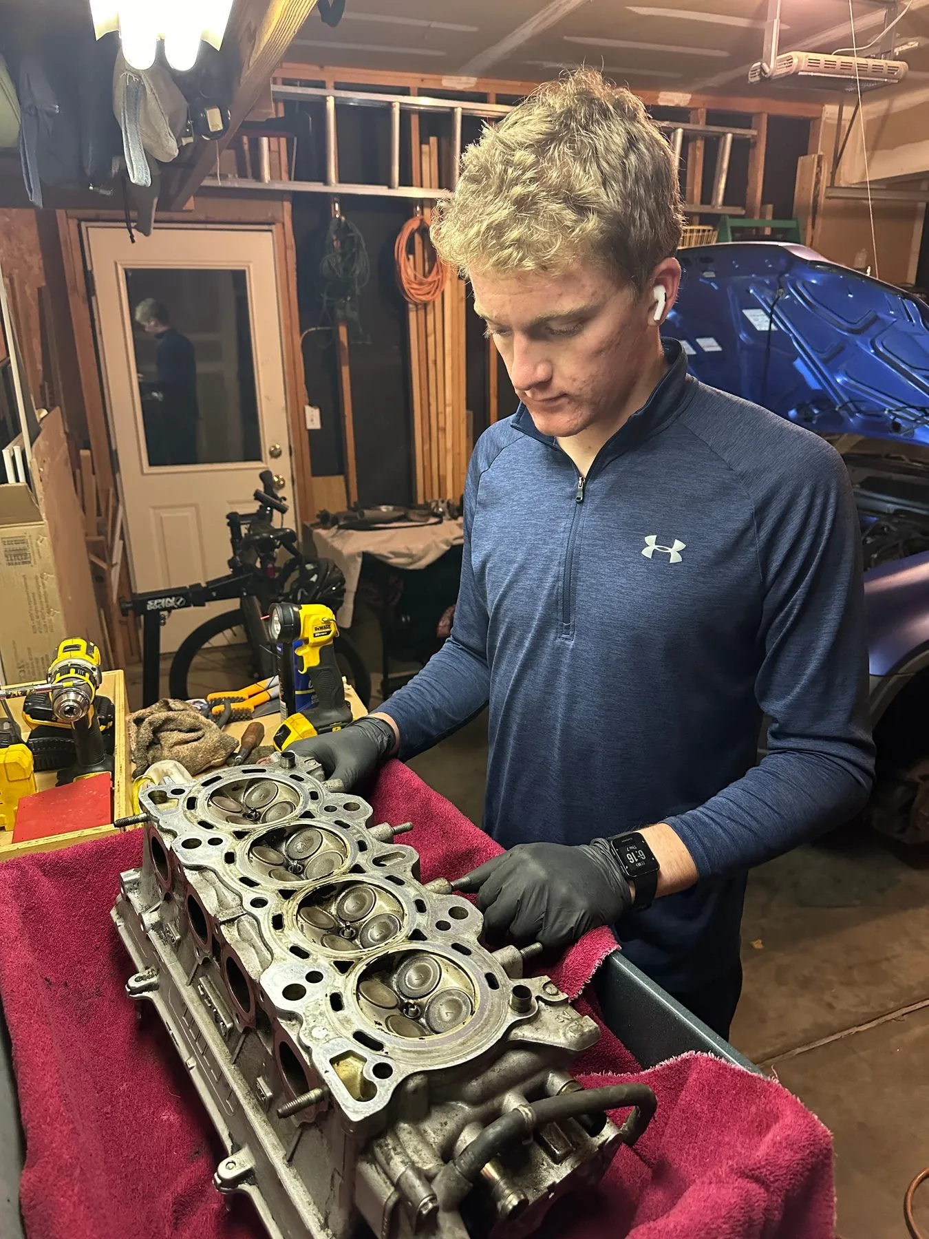 Inspecting a four-cylinder engine head laid on a red shop towel in the garage
