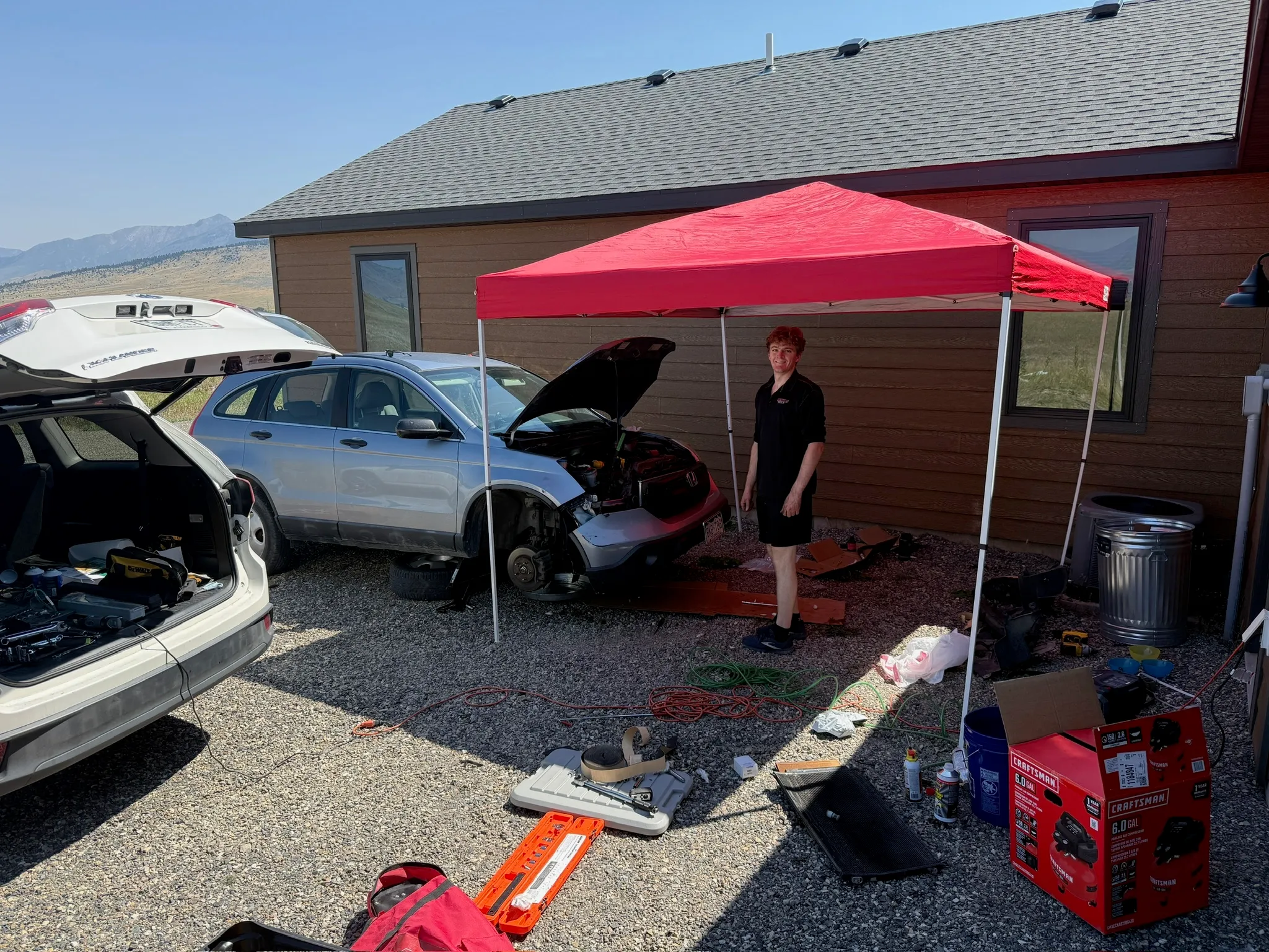 The repair set up in the rental driveway, tools laid out under a pop-up canopy