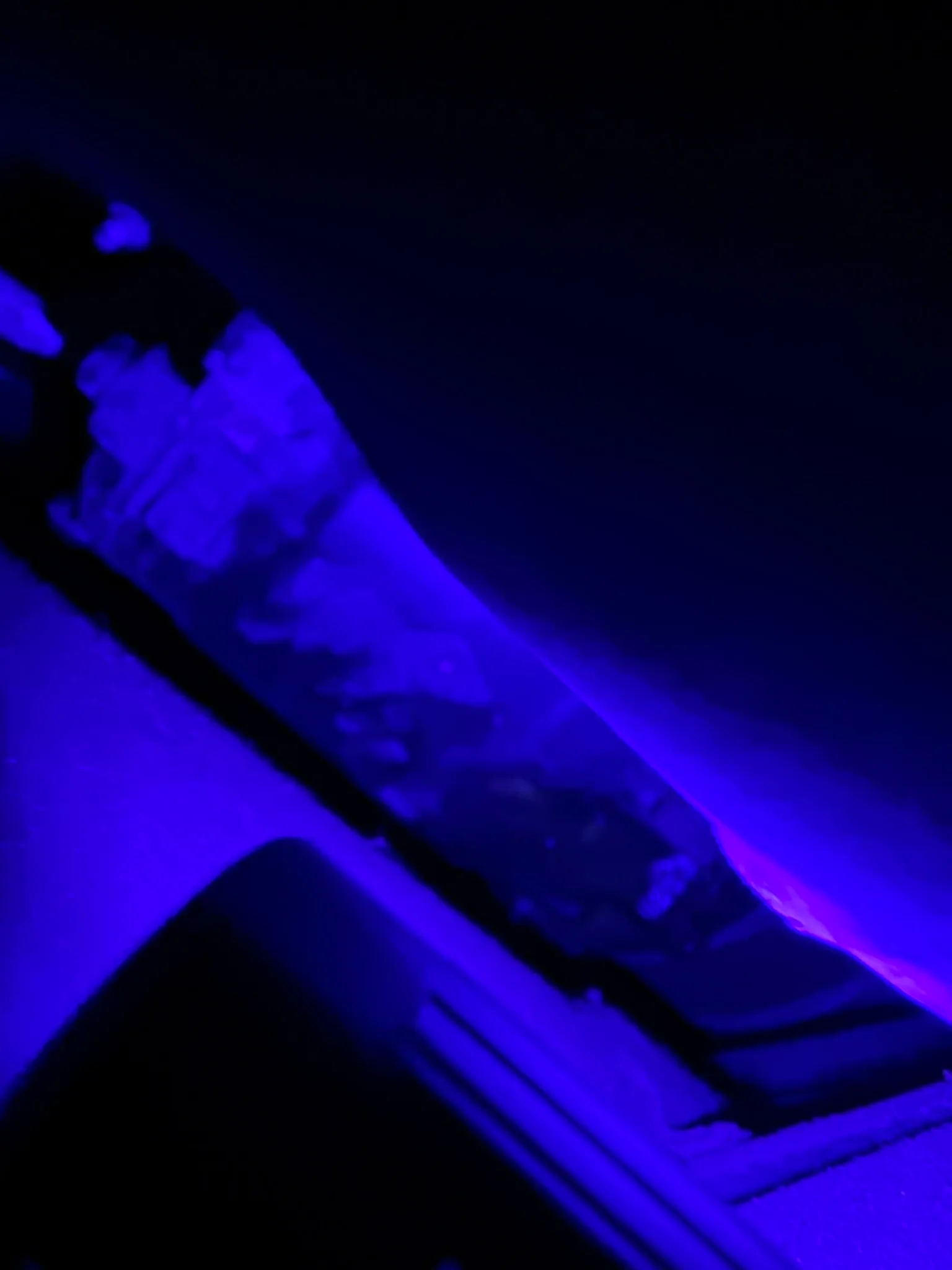 The leak located under UV light, the dye fluorescing against the surrounding components